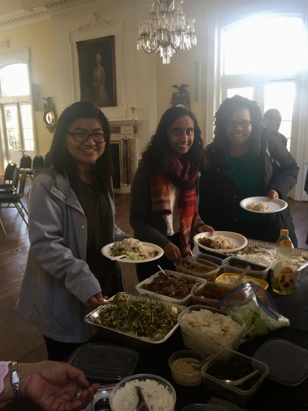 three people holding plates by a buffet