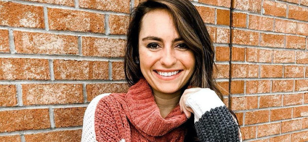 smiling woman in front of brick wall