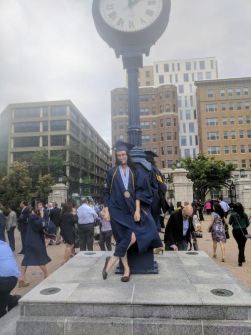 Robyn in front of clock in graduation gown