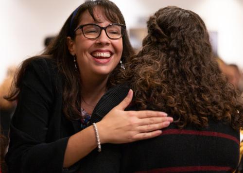 Woman smiles and hugs another person